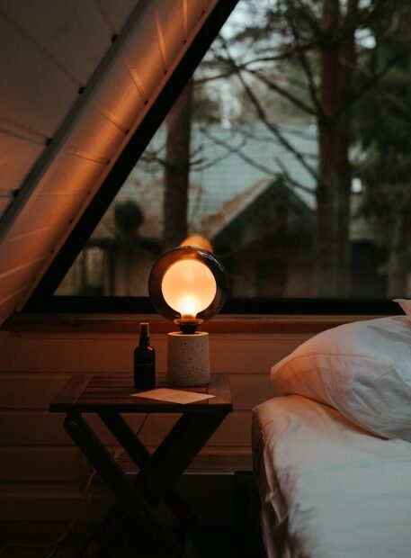 ein Bett, das unter einem Fenster neben einem Nachttisch steht